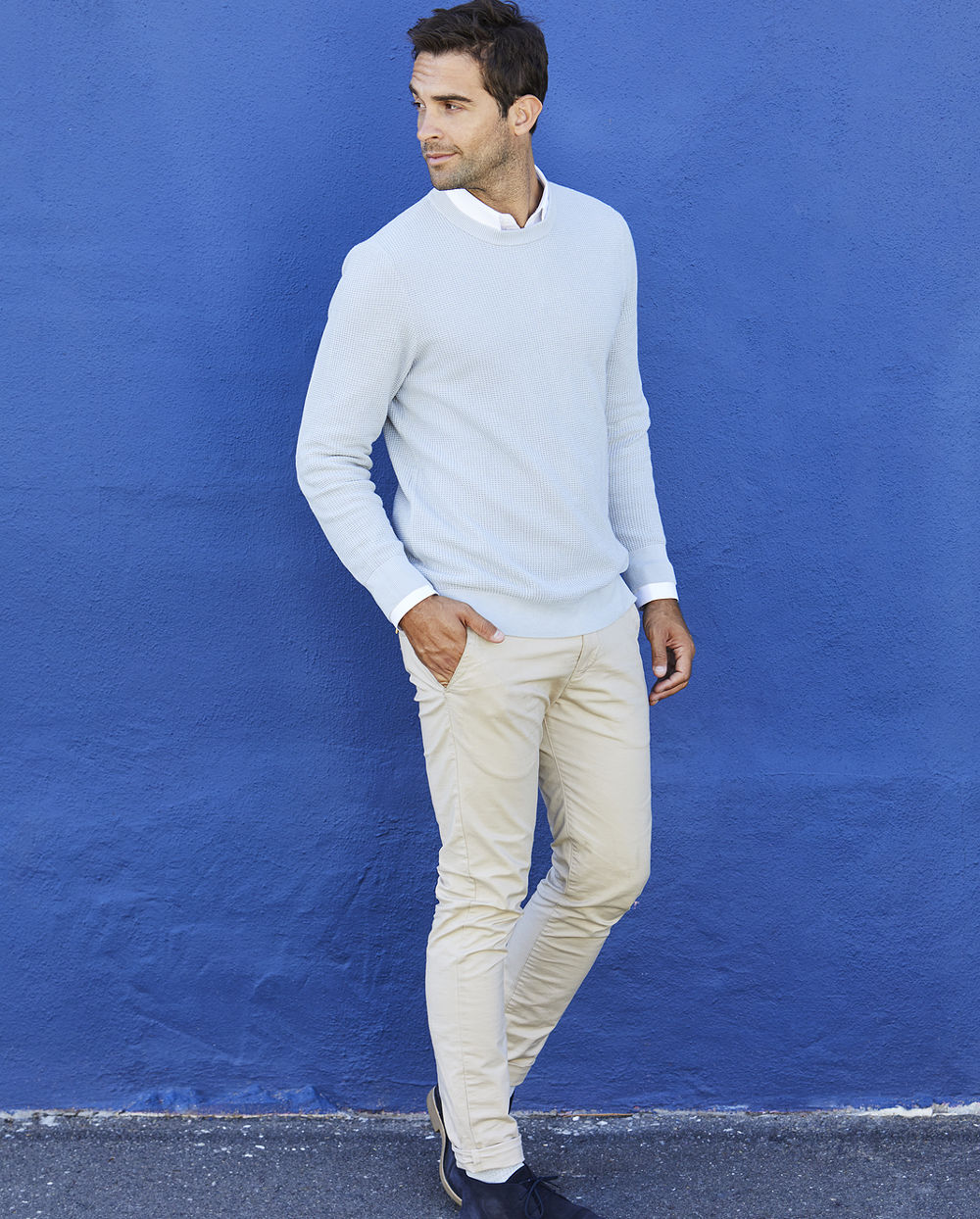 Man in blue sweater and chinos looking away