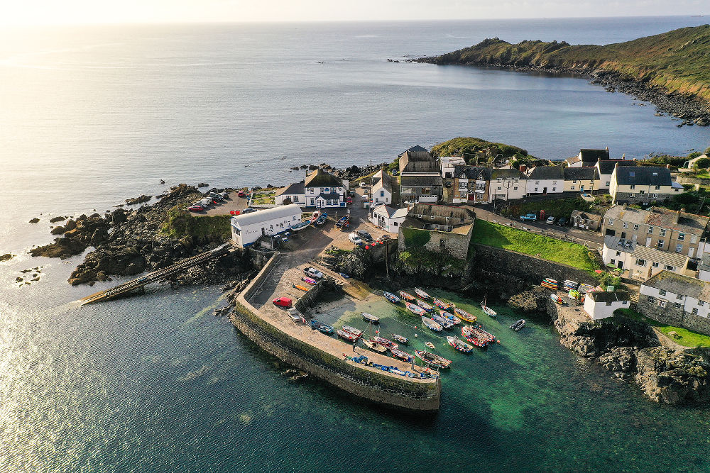 An aerial landscape image by drone of the picturesque Cornish fishing village and harbour of Coverack in Cornwall, UK