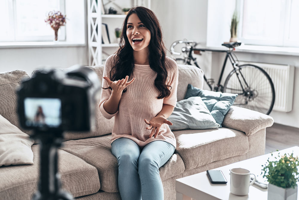 Modern influencer. Female vlogger making social media video while sitting indoors