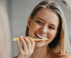 Oral hygiene, healthy teeth and care. Young woman brushing teeth with toothbrush and looking in mirror in bathroom