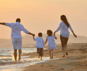 happy young family have fun on beach run and jump at sunset