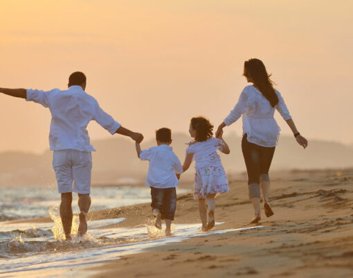 happy young family have fun on beach run and jump at sunset