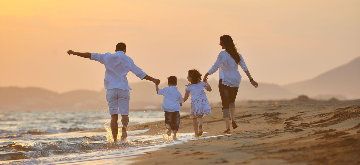 happy young family have fun on beach run and jump at sunset