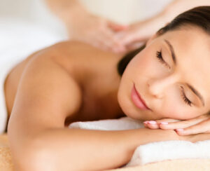 health, beauty, resort and relaxation concept - beautiful woman with closed eyes in spa salon getting massage