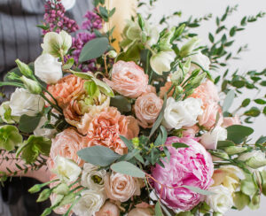 Rich bunch of pink peonies and white eustoma roses flowers, green leaf in glass vase