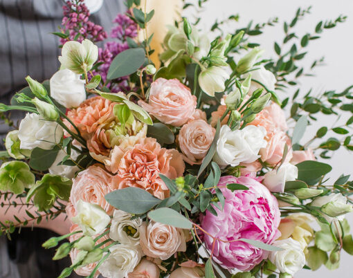 Rich bunch of pink peonies and white eustoma roses flowers, green leaf in glass vase