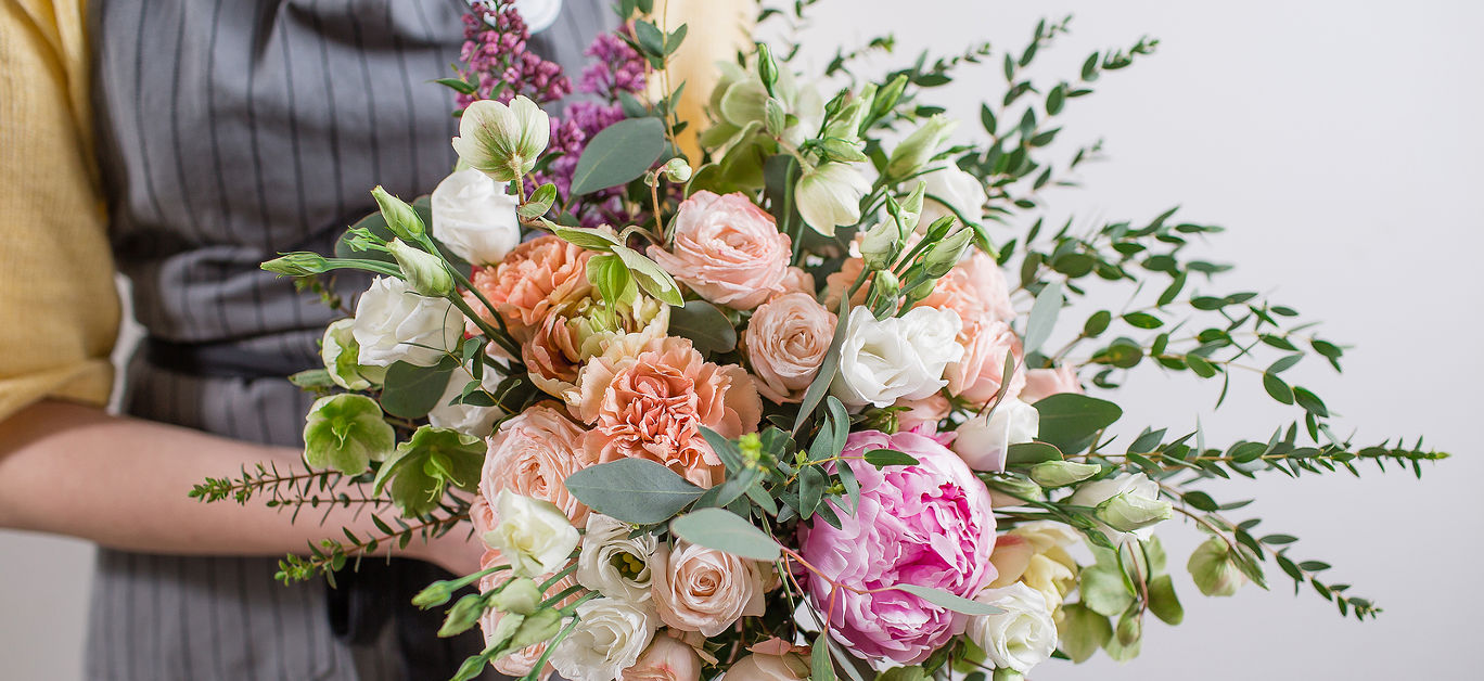 Rich bunch of pink peonies and white eustoma roses flowers, green leaf in glass vase