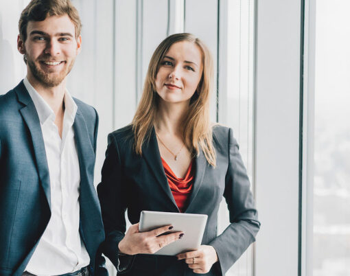 Group of business people a man in a suit and a woman in a red dress and jacket holding a tablet winter city landscape outside the window on the background