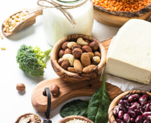 Vegan protein source. Tofu, vegan milk, beans, lentils, nuts, broccoli spinach and seeds on white table with copy space. Healthy balanced vegetarian food.