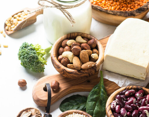 Vegan protein source. Tofu, vegan milk, beans, lentils, nuts, broccoli spinach and seeds on white table with copy space. Healthy balanced vegetarian food.