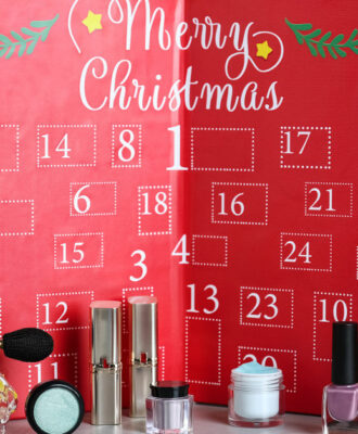 Advent calendar with different cosmetics and perfumes on light grey table. Presents for Christmas