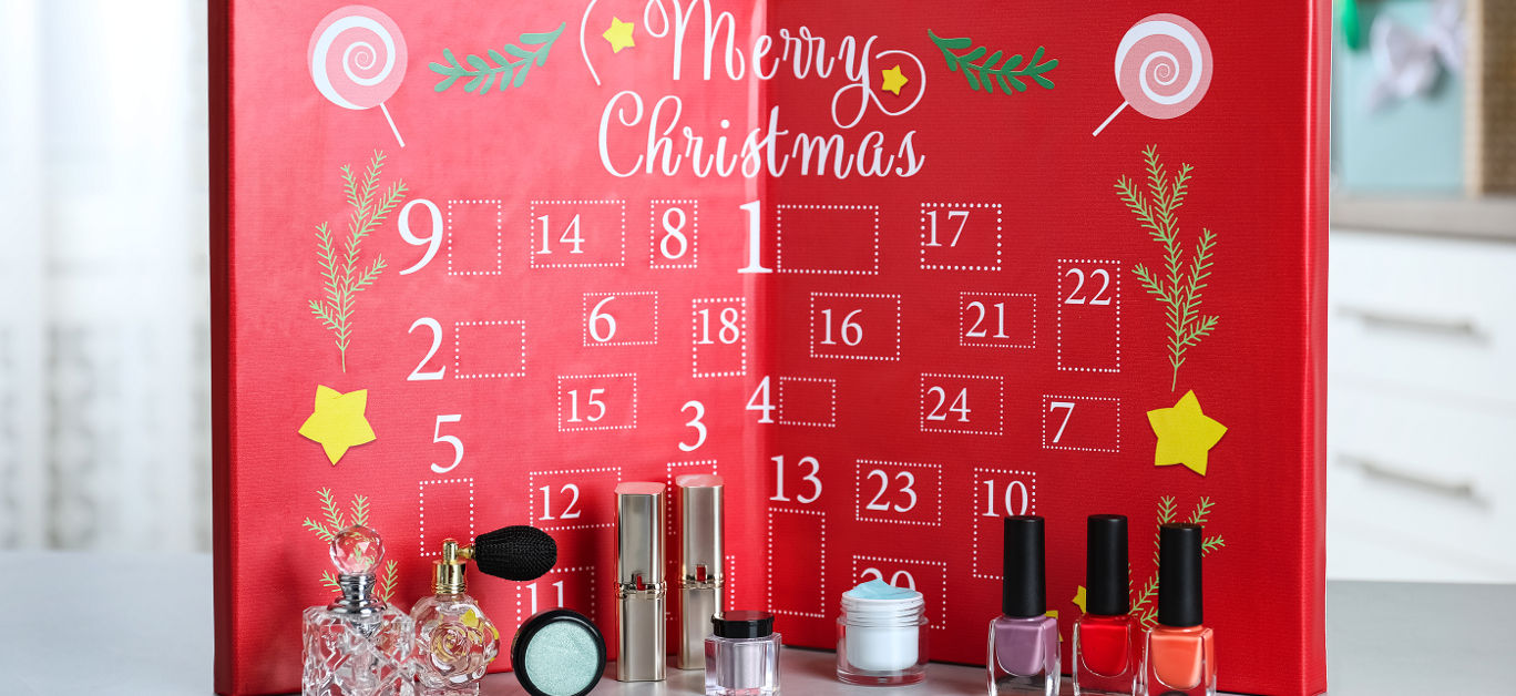 Advent calendar with different cosmetics and perfumes on light grey table. Presents for Christmas