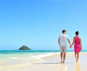 Beach honeymoon couple holding hands walking on white sand beach