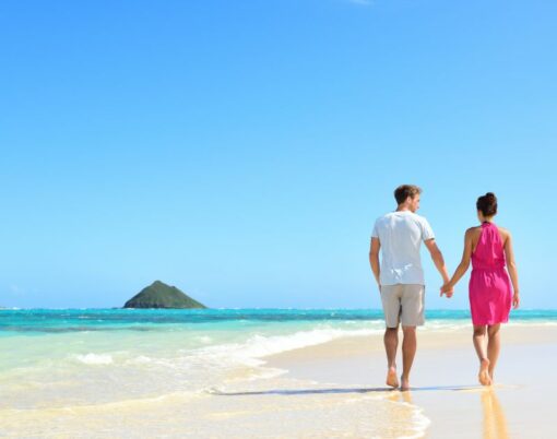 Beach honeymoon couple holding hands walking on white sand beach