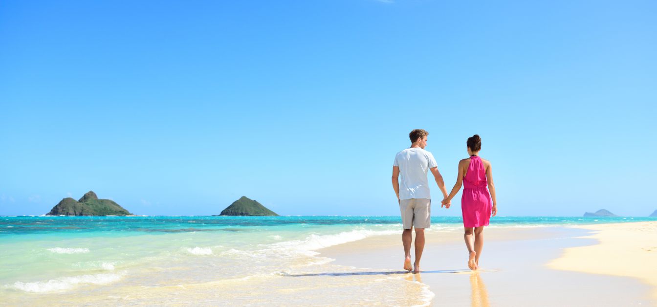 Beach honeymoon couple holding hands walking on white sand beach