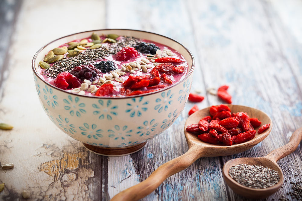 Breakfast berry smoothie bowl topped with goji berries,raspberry, blackberry, pumpkin, sunflower and chia seeds. soft focus