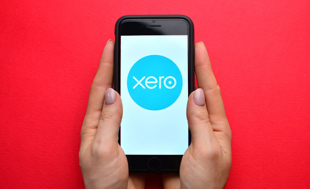 Illustrative editorial of Xero logo on smartphone screen in female hands.