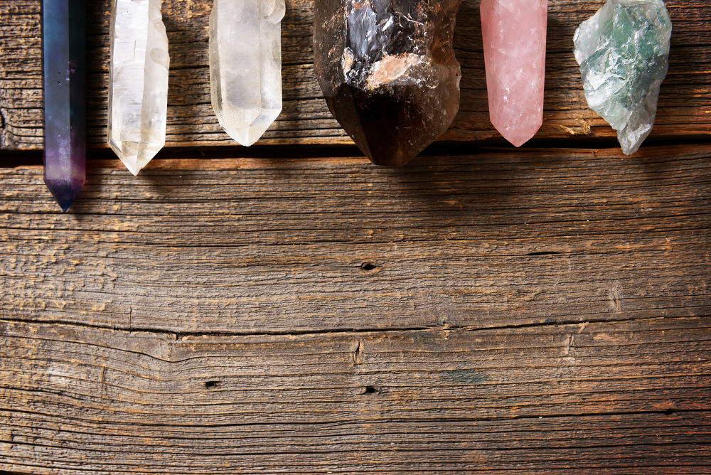 Multiple semi precious gemstones on wooden board fluorite, quartz, smoky quartz, rose quartz.