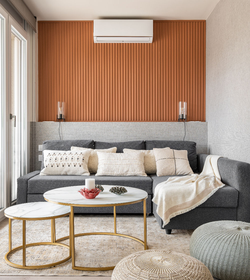 Vertical shot of a stylish living room with terracotta wall, sofa and modern interior accessories table and pouffes. 