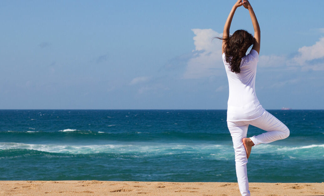 young woman doing yoga on beach