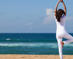 young woman doing yoga on beach