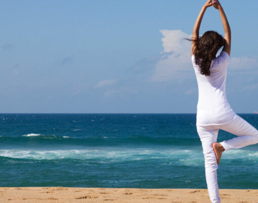 young woman doing yoga on beach