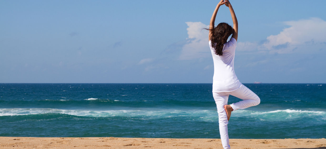 young woman doing yoga on beach