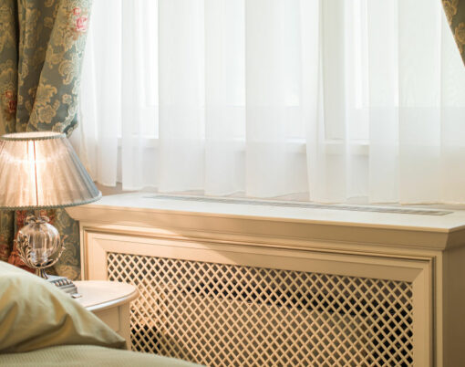 Wooden cover for radiator near window in home interior