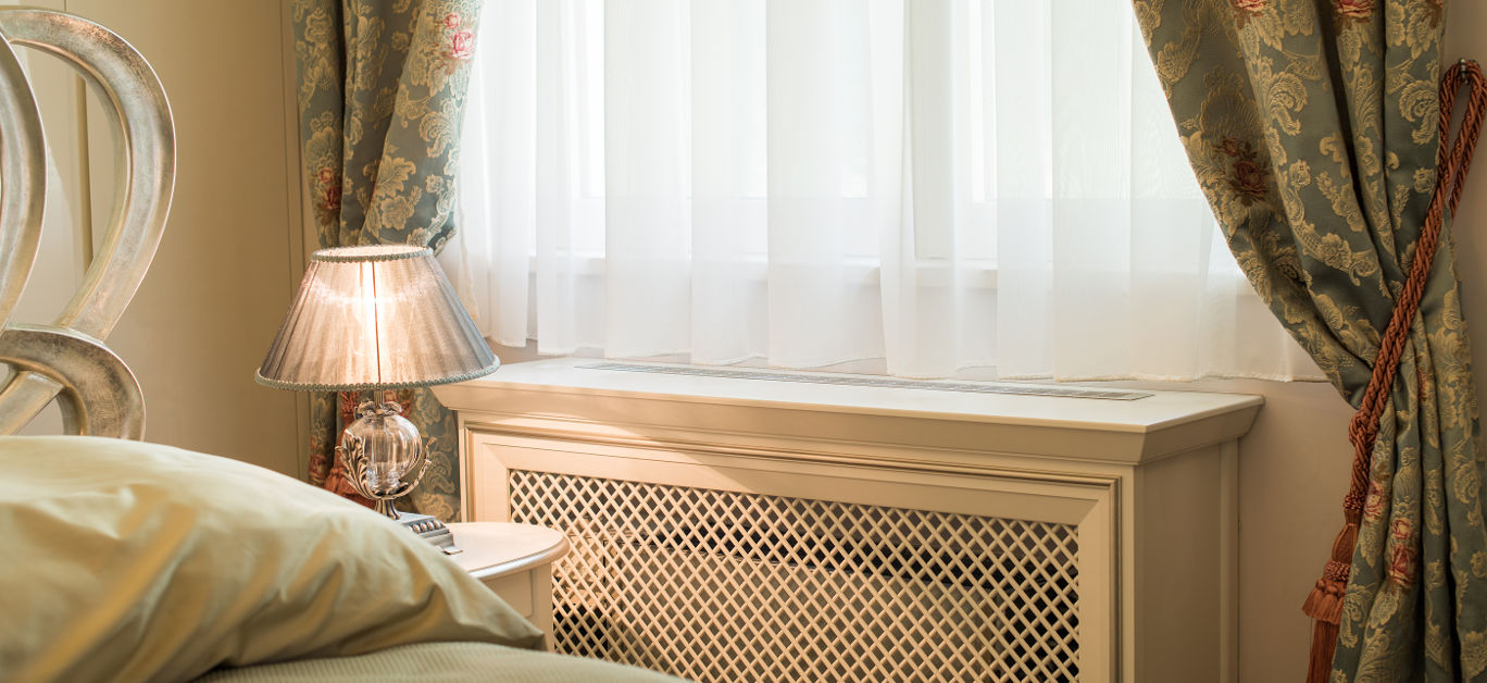 Wooden cover for radiator near window in home interior