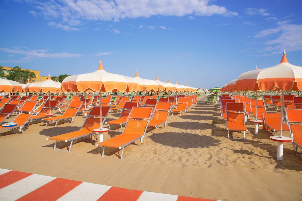 Orange umbrellas and chaise lounges on the beach of Rimini in Italy