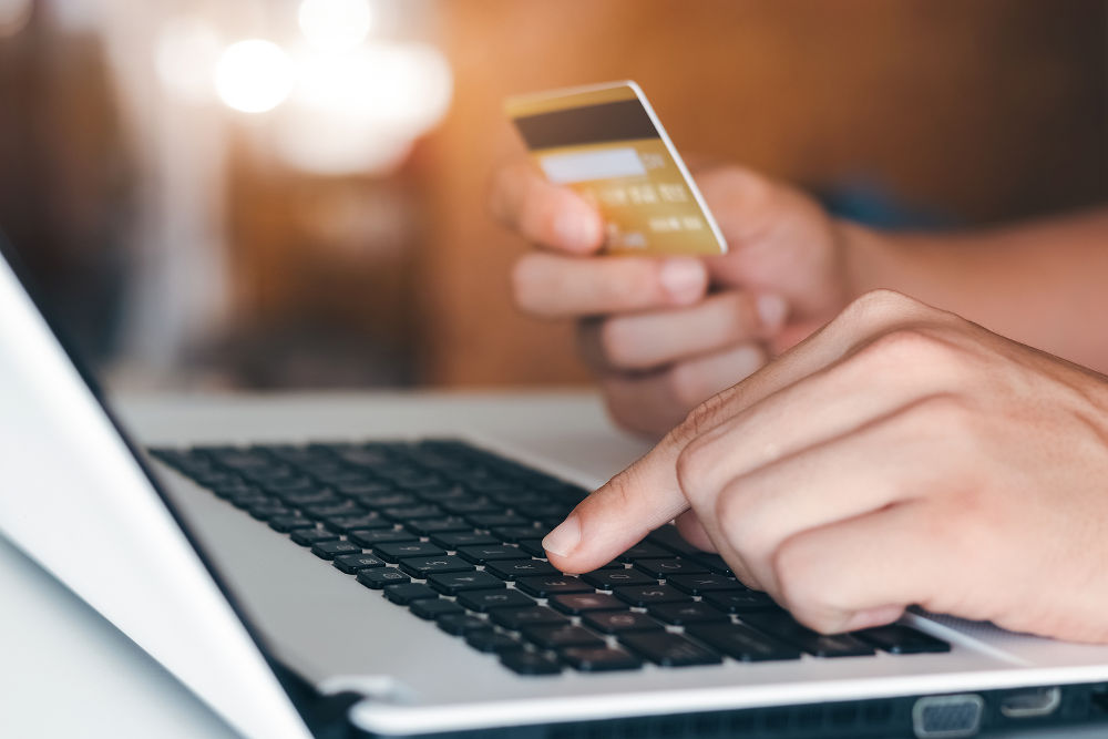 Businessman hand holding credit card with using laptop for online shopping while making orders at home