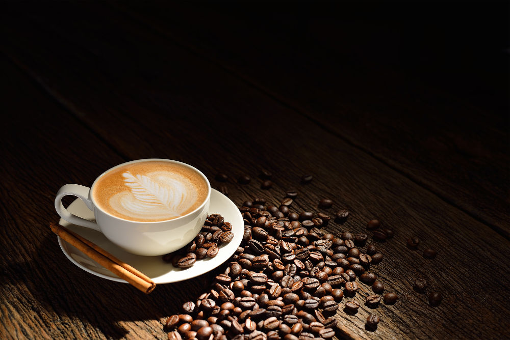 Cup of cafe latte and coffee beans on old wooden background