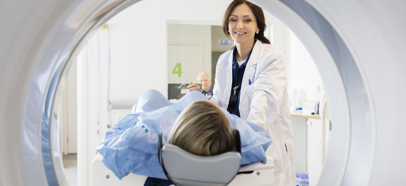 Female Doctor Looking At Patient Undergoing CT Scan