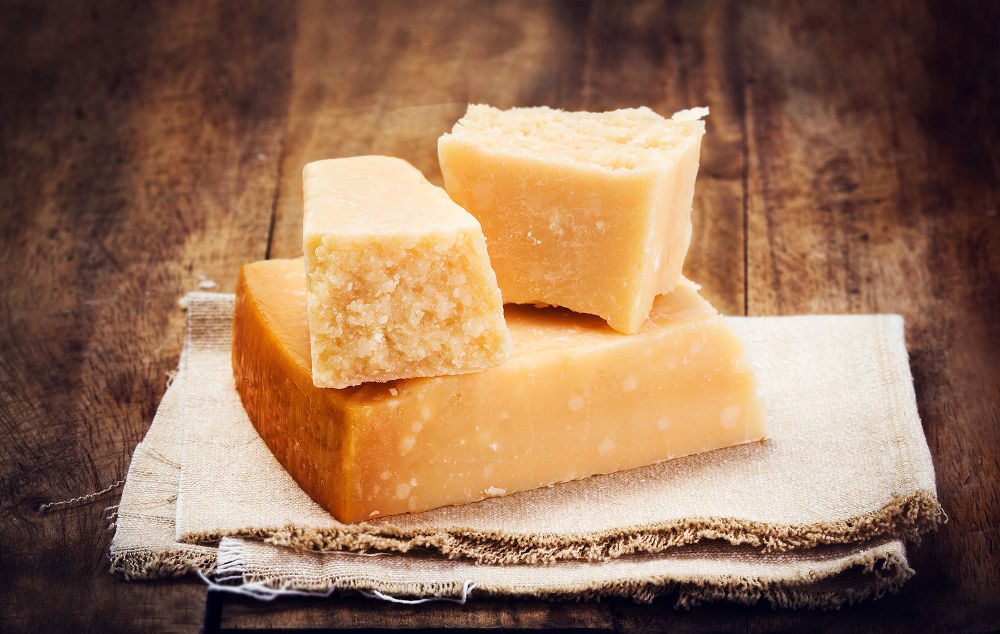 Italian Parmesan Cheese on Wooden Background close up. Piece of Parmigiano cheese on a napkin rustic style.