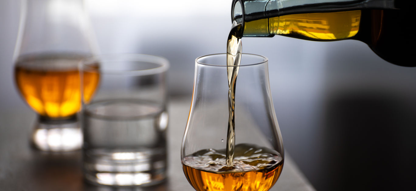 Pouring in tulip-shaped tasting glass Scotch single malt or blended whisky and glas of water