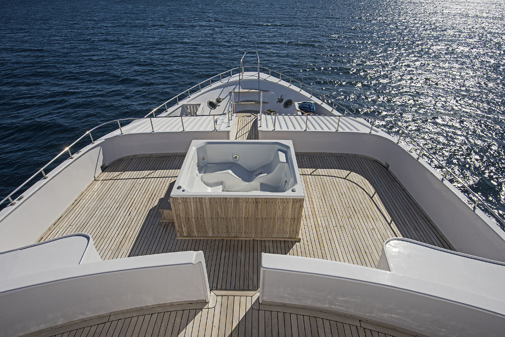 View over the bow of a large luxury motor yacht on tropical open ocean with hot tub