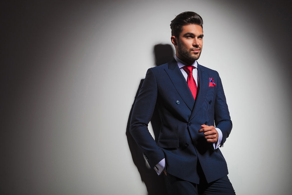 side view of an arrogant stylish man in suit and tie posing in studio, looking to a side 