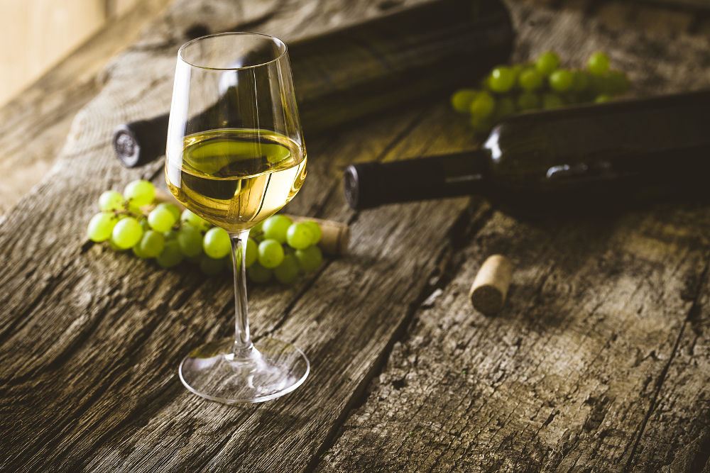 Wine. Glass of white wine in wine cellar. Old white wine on wood.