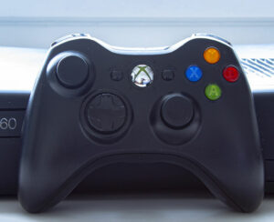 An Xbox 360 console with a control remote on a white table.