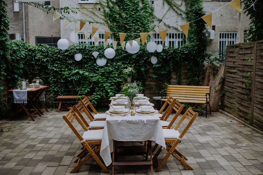 Festive wedding table setting with flowers at small reception in backyard in summer.