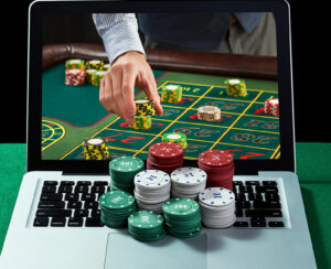 Green table with casino chips, cards on notebook, image of poker player on screen of laptop. Concept for online gambling