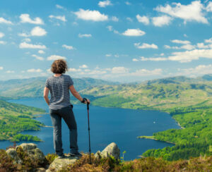 Hiking woman on top of the Mountain in Ben A'an Hill, Highlands, Scotland, Panoramic Shot - Panorama Of Landscape View From Ben A'an Hill, Highlands, Scotland