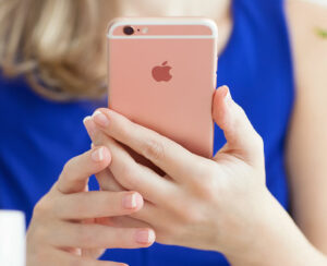 Woman holding in the hand iPhone6S Rose Gold in cafe.