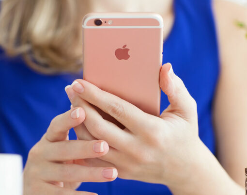 Woman holding in the hand iPhone6S Rose Gold in cafe.