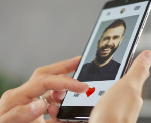 Woman holding mobile phone gives like to young man on online dating app or website