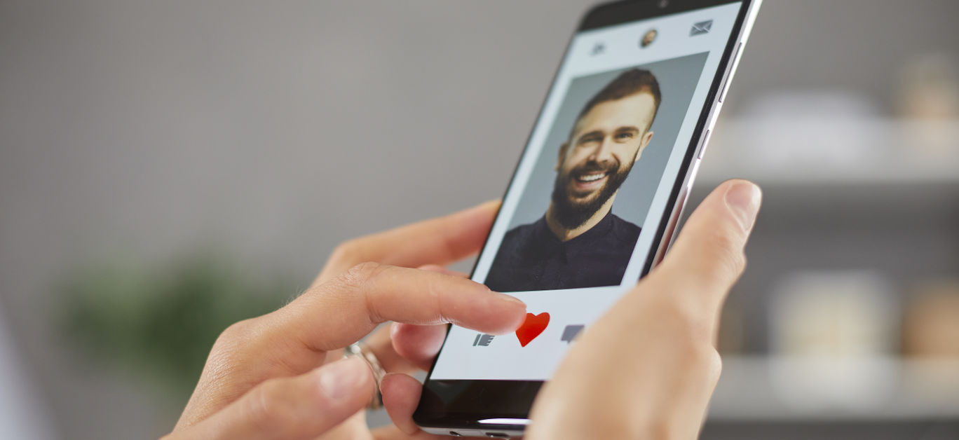 Woman holding mobile phone gives like to young man on online dating app or website